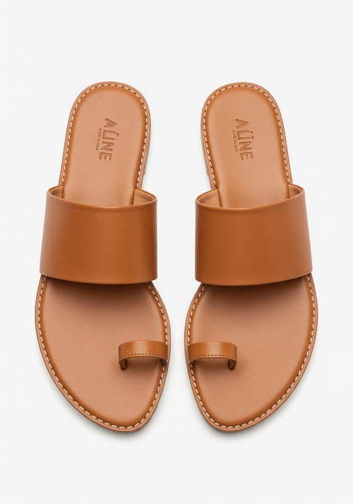 Pair of brown sandals with 'ALINE' branding on a light gray background