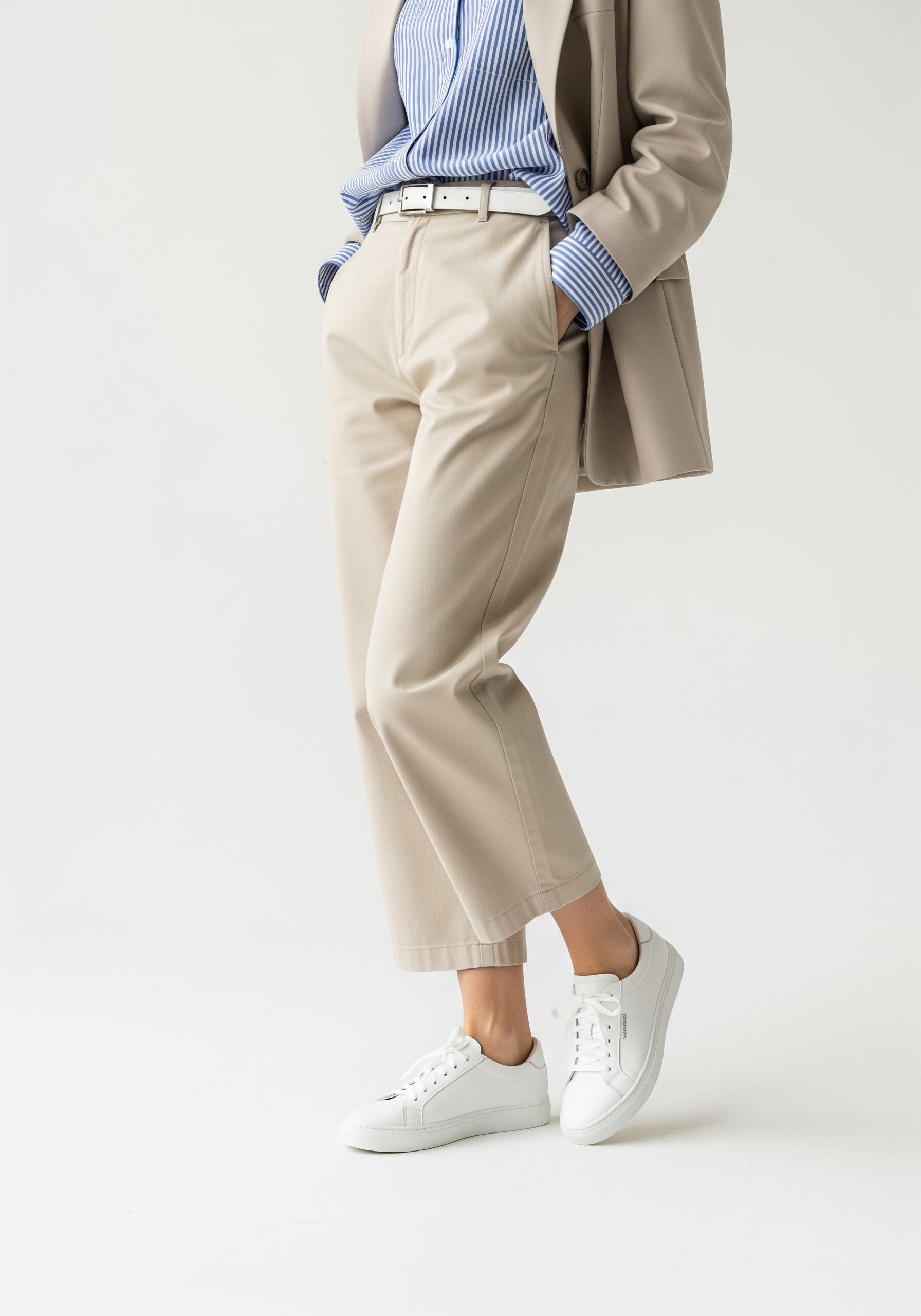 Person wearing a beige suit with a blue shirt and white sneakers on a light background